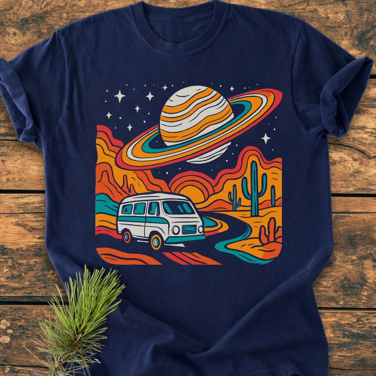 Psychedelic Van Journey - Vintage Wash Tee features a retro camper van on a desert road, surrounded by abstract rock formations and cacti, under a ringed planet and starry sky.