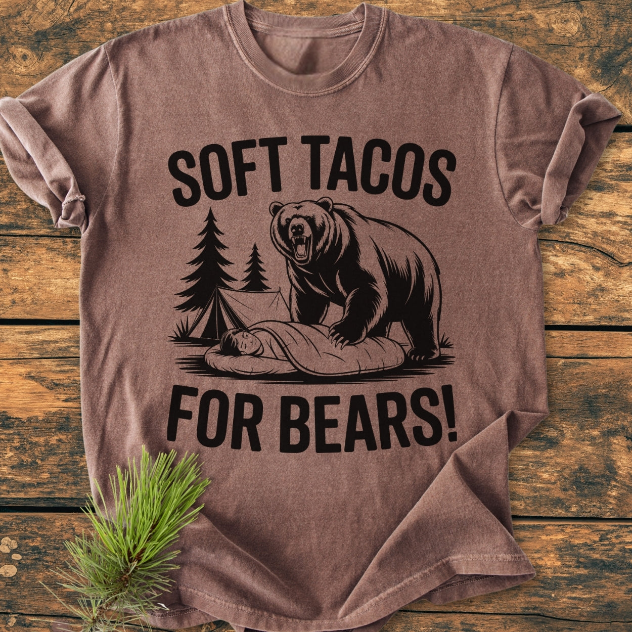 Soft Tacos For Bears - Vintage Wash Tee features a cartoon bear campsite print on a brown T-shirt, laid flat on a rustic wood surface, highlighting its relaxed fit and durable craftsmanship.