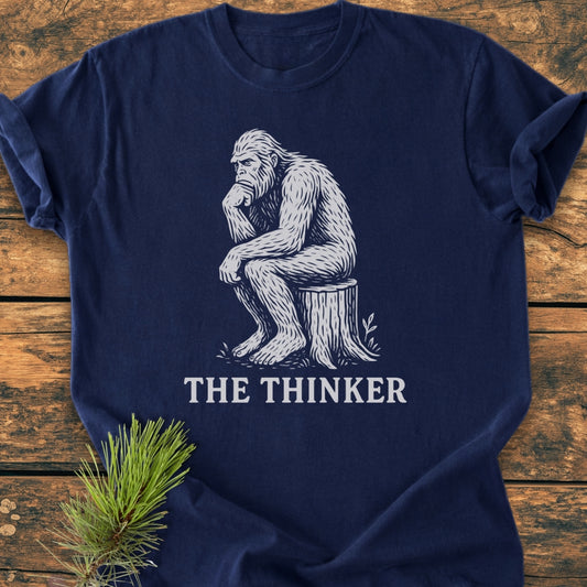 Bigfoot The Thinker - Vintage Wash Tee features a white graphic of a Sasquatch in a thoughtful pose on a navy-blue T-shirt, made from soft, durable, 100% ring-spun cotton.
