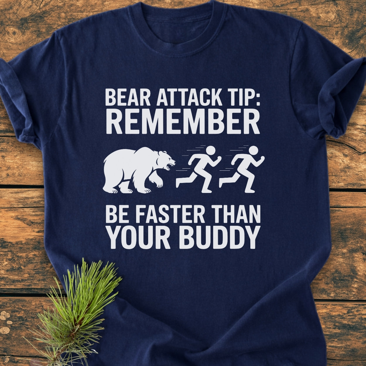 Bear Attack Tip Be Fast - Vintage Wash Tee features a cartoon bear and stick figures graphic with humorous text, laid out on wood with a pine branch, showcasing a relaxed, durable design.