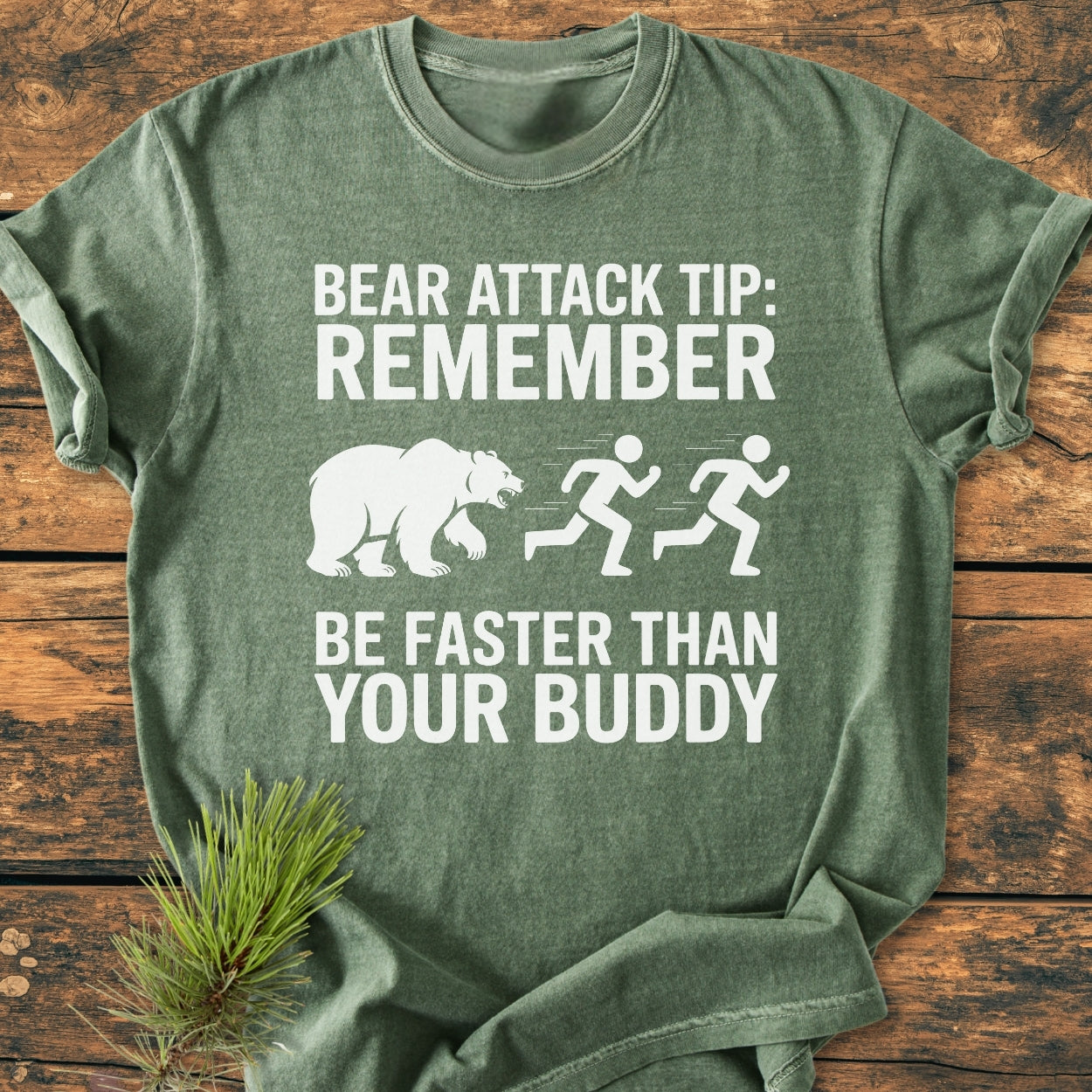 Bear Attack Tip Be Fast - Vintage Wash Tee features a humorous bear attack tip with simple graphics, laid flat with a pine sprig, illustrating its relaxed fit and soft-washed fabric.