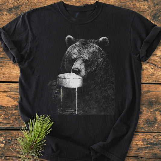 Grizzly With Beer - Vintage Wash Tee featuring a grayscale bear sipping beer, laid flat on wood. Crafted from 100% ring-spun cotton, this relaxed fit tee offers durability and comfort.