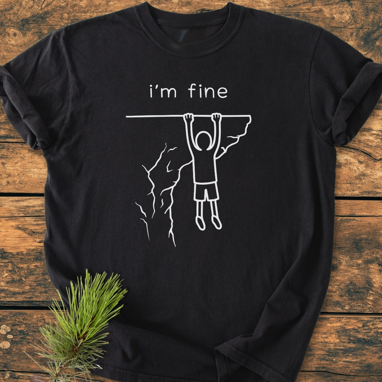 I'm Fine - Vintage Wash Tee features a stick-figure dangling from a cliff with i’m fine. caption, highlighting its relaxed fit and durability, made from soft-washed, garment-dyed 100% ring-spun cotton.