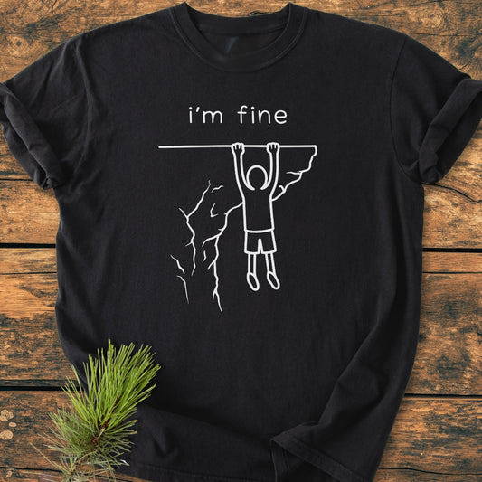 I'm Fine - Vintage Wash Tee features a stick-figure dangling from a cliff with i’m fine. caption, highlighting its relaxed fit and durability, made from soft-washed, garment-dyed 100% ring-spun cotton.