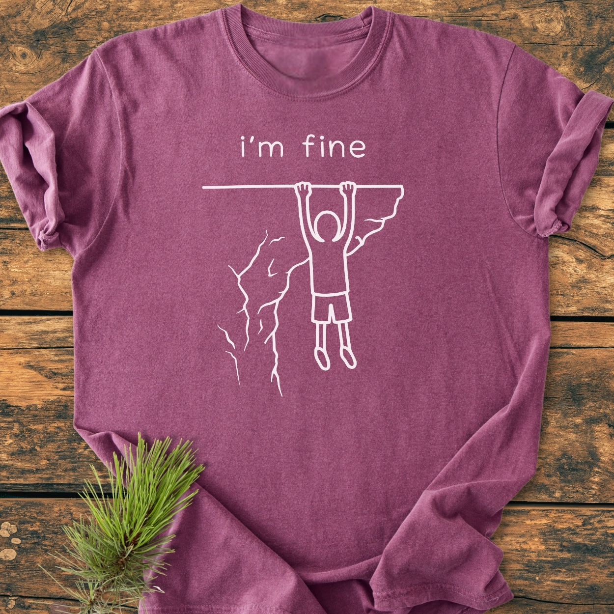 I'm Fine - Vintage Wash Tee in heather-purple, featuring a stick-figure design with i’m fine. text. Laid on wood, with a pine twig beside. Made of soft, durable ring-spun cotton.