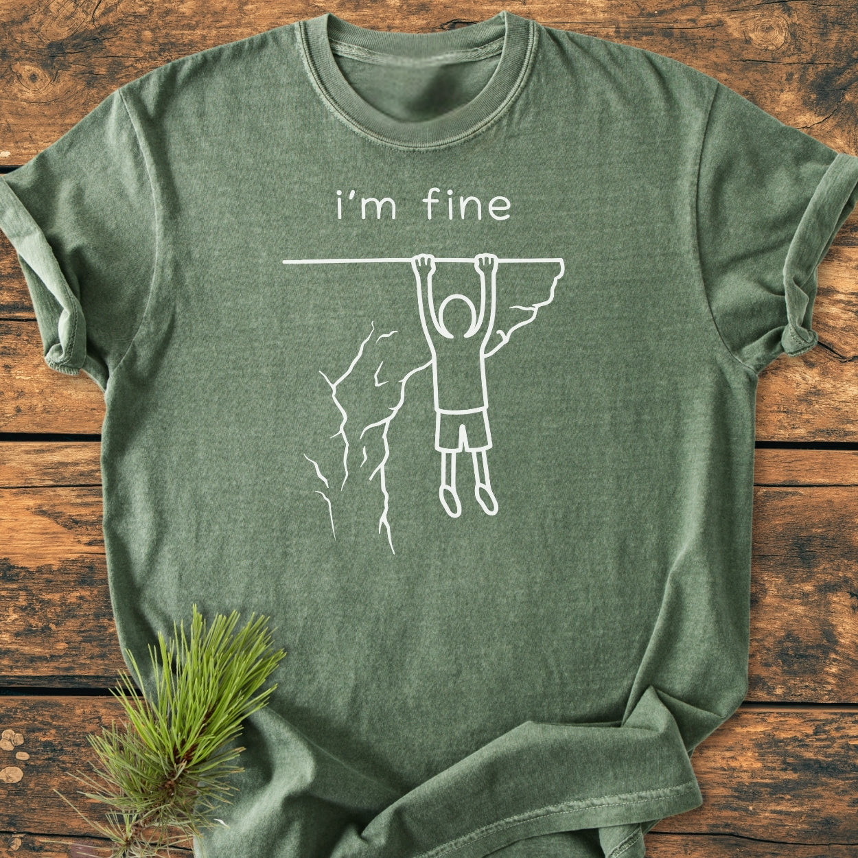 I'm Fine - Vintage Wash Tee: Heather-green T-shirt with I’m fine text and stick figure art, featuring a relaxed fit and soft-washed fabric for comfort, laid on a wooden surface.