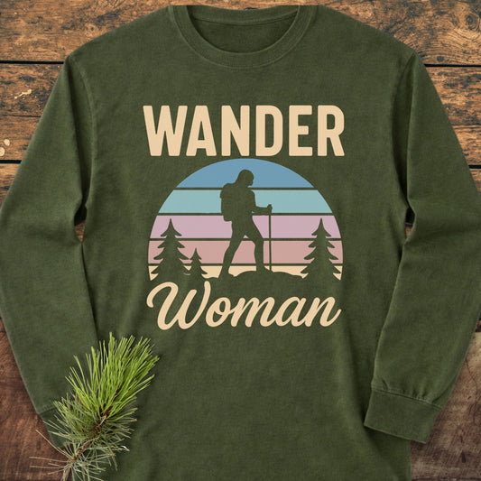 Wander Woman Retro Long-Sleeve Tee featuring a circular graphic of a woman hiker with trekking poles, surrounded by pine trees, printed on an olive-green, garment-dyed cotton tee for a relaxed fit.