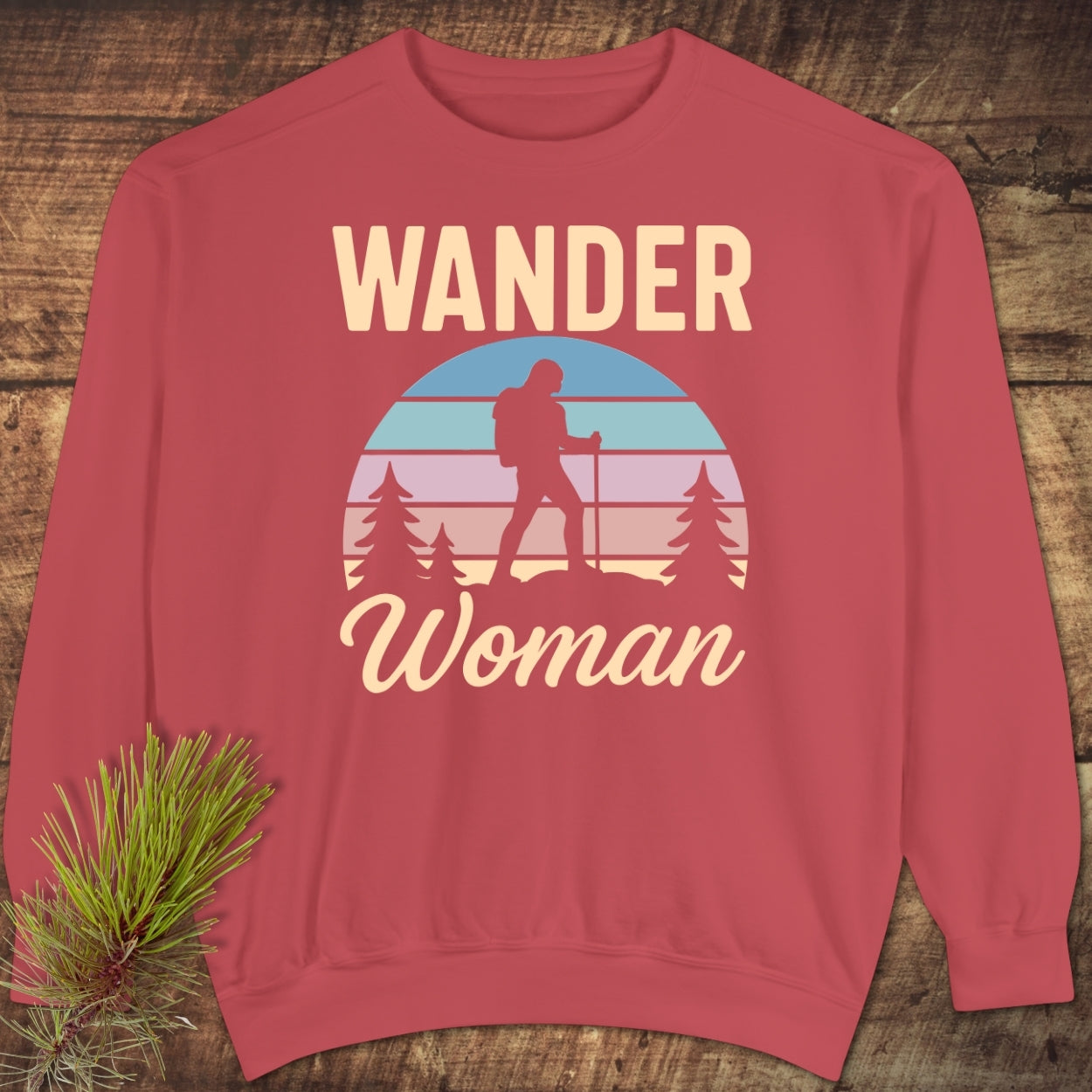 Wander Woman Retro Sweatshirt features a hiker silhouette against a pastel sunset with trees, “WANDER” above. It's a relaxed-fit, garment-dyed, cotton-polyester blend offering luxurious comfort and style.