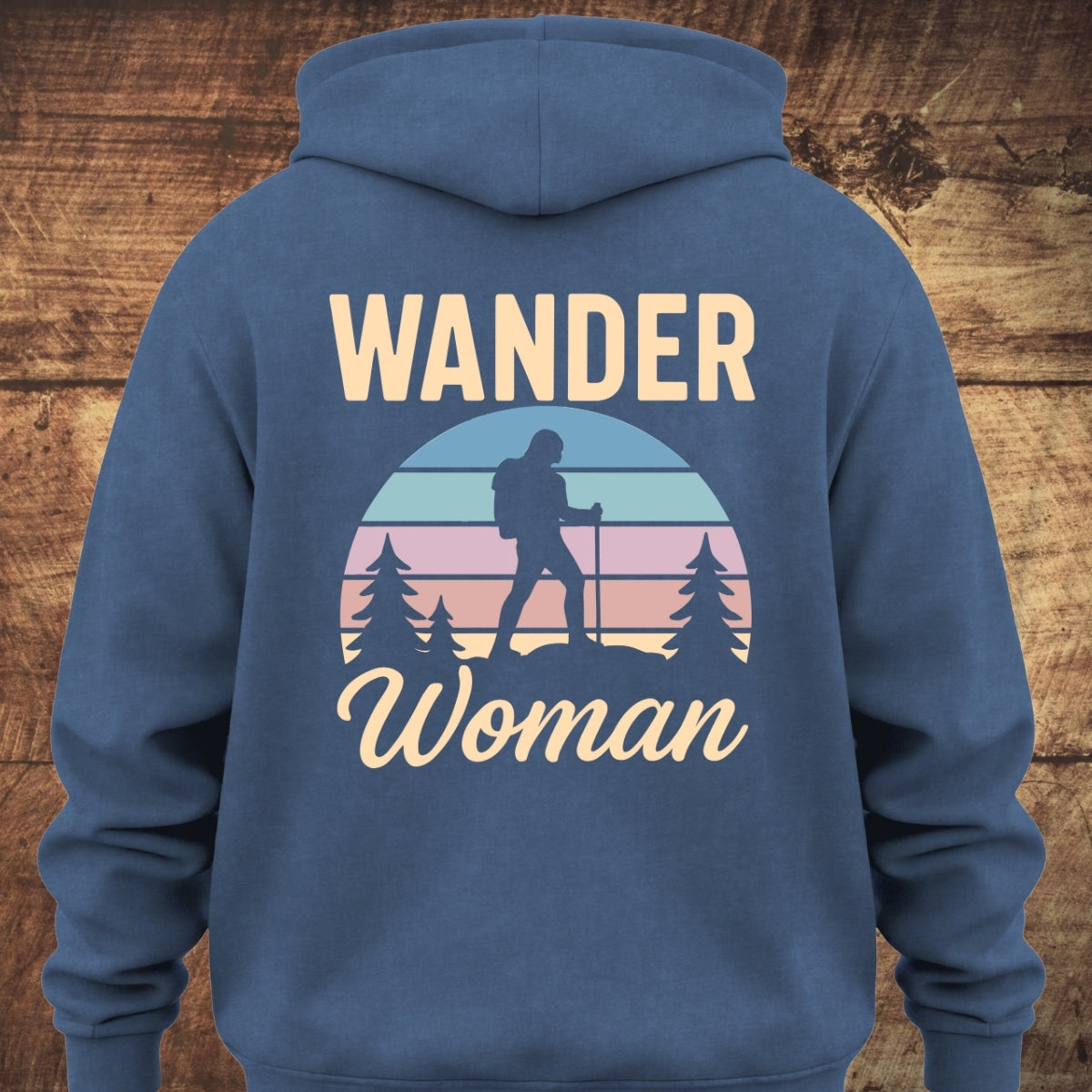 Back of the Wander Woman Retro Hoodie, featuring a circular sunset graphic with a silhouetted hiker and pine trees, framed by WANDER above and Woman below, on a soft, unisex garment-dyed hoodie.