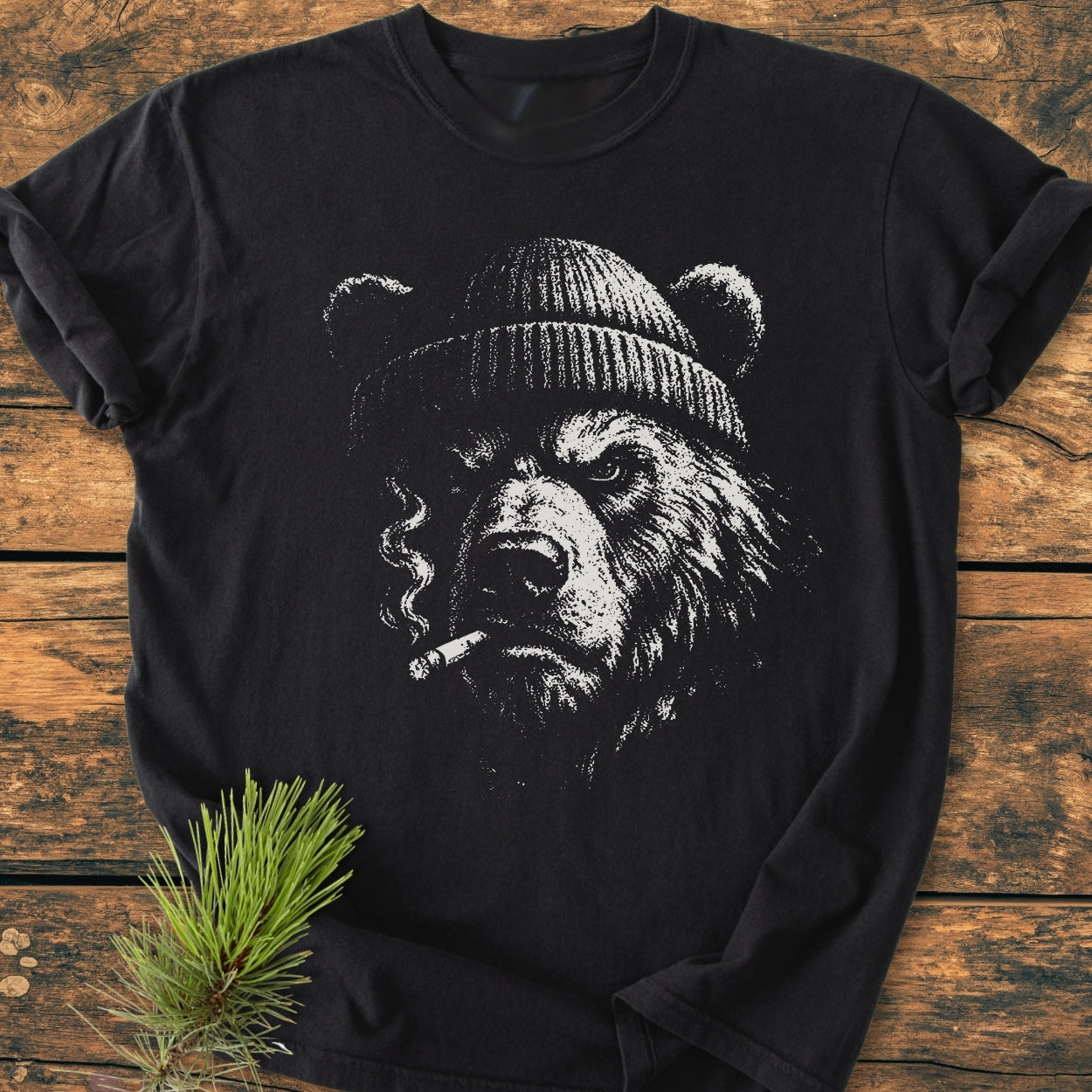 Smoking Bear - Vintage Wash Tee featuring a gritty bear illustration with a beanie and cigarette, laid on rustic wood. Crafted from soft, durable, garment-dyed cotton for a relaxed fit.