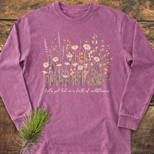 Let's Get Lost In A Field Of Wildflowers Long-Sleeve Tee features stylized wildflowers and text on a soft, relaxed-fit cotton shirt, adorned with a pine sprig for a natural touch.