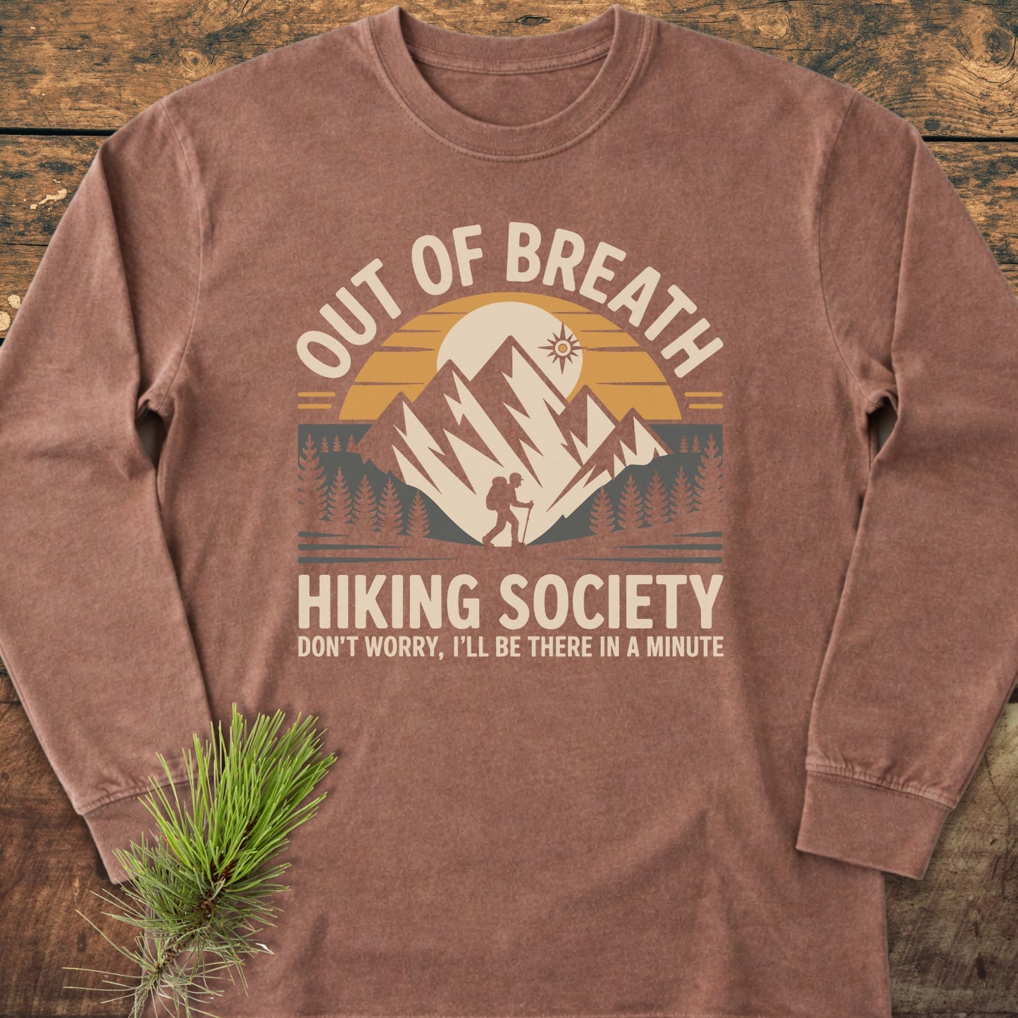 Out Of Breath Hiking Society Long-Sleeve Tee features a vintage-washed brown design with a retro graphic of a sunset behind mountains, a lone hiker, and humorous text.