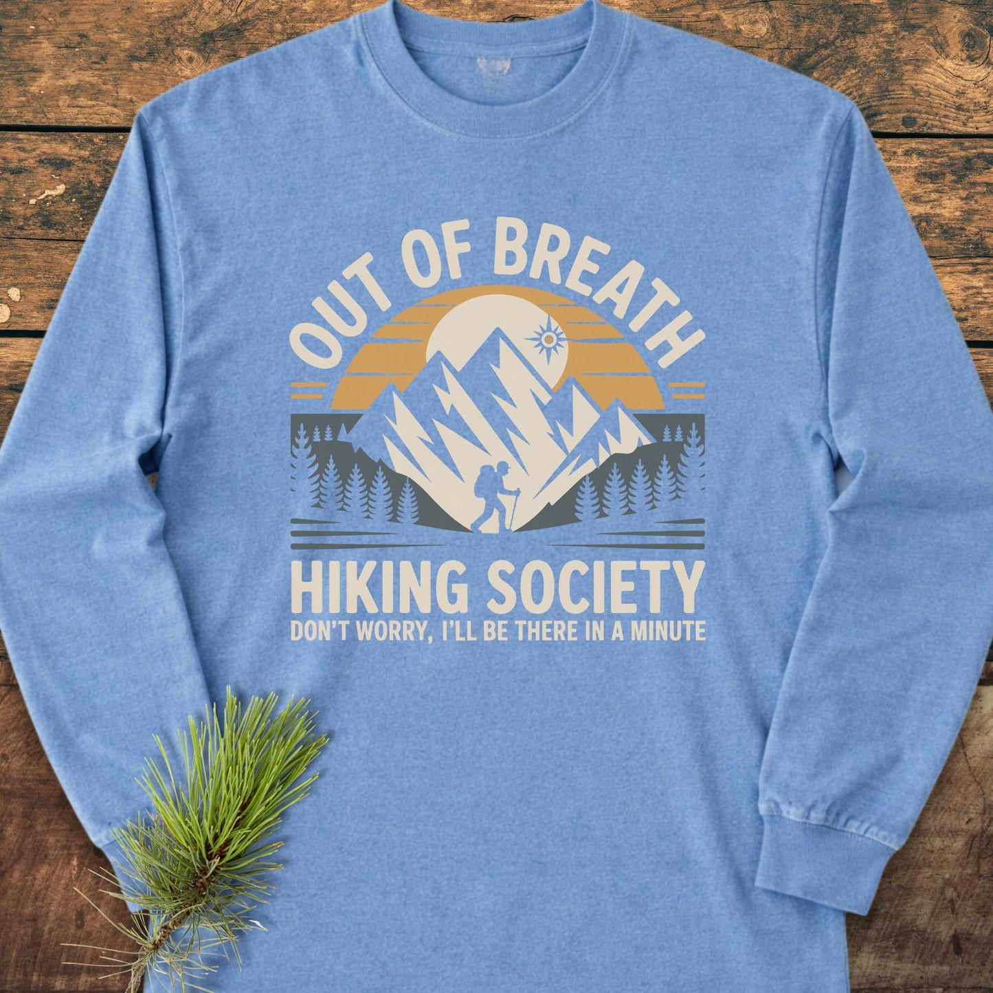 Out Of Breath Hiking Society Long-Sleeve Tee with a sunset, mountains, lone hiker, and humorous slogan, offering a relaxed fit in soft, garment-dyed cotton for outdoor enthusiasts.