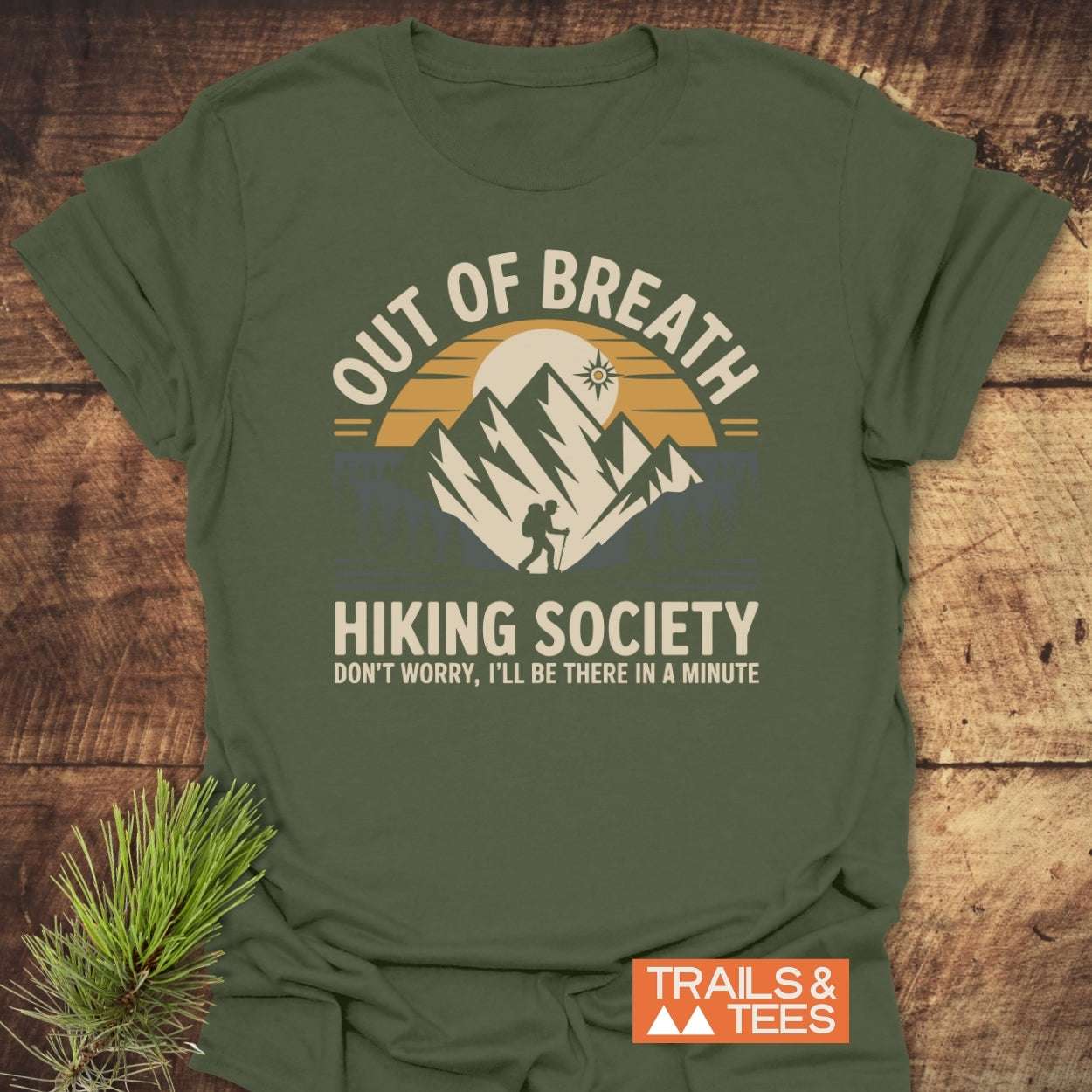 Out Of Breath Hiking Society T-Shirt featuring a vibrant outdoor graphic with a setting sun, mountain peaks, and a backpacker. Crafted from soft cotton, highlighting adventure-ready comfort and style.