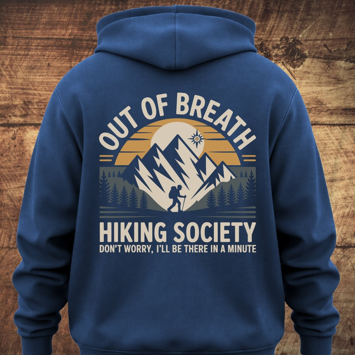 Out Of Breath Hiking Society BACKPRINT hoodie features a mountain range graphic with a hiker silhouette and text, offering a relaxed fit, ideal for outdoor adventures or lounging.