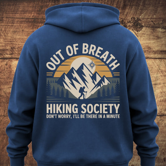 Out Of Breath Hiking Society BACKPRINT hoodie features a mountain range graphic with a hiker silhouette and text, offering a relaxed fit, ideal for outdoor adventures or lounging.