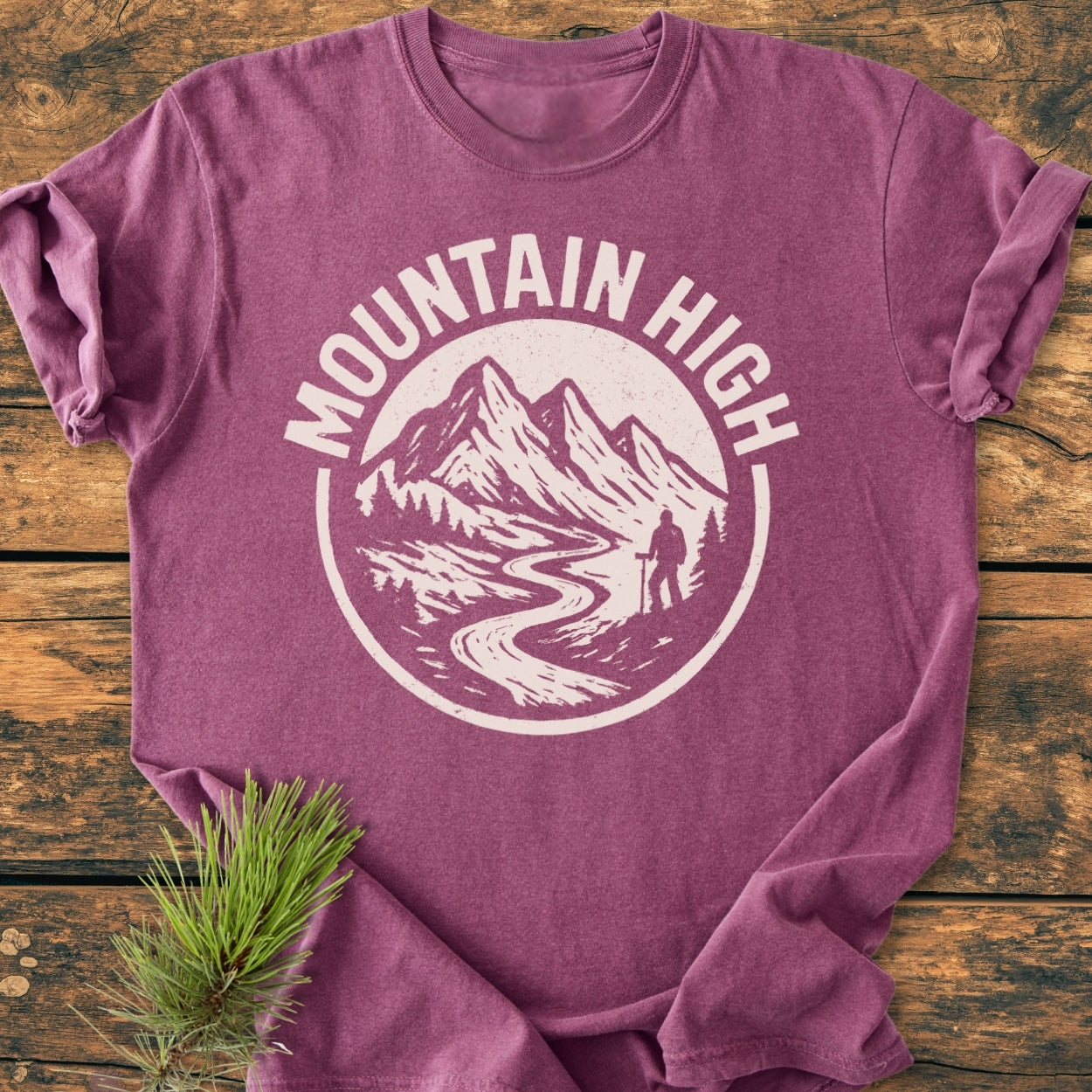 Mountain High - Vintage Wash Tee in purple-heather, featuring a cream graphic of mountains and a hiker, laid on wood. Soft-washed, relaxed fit, 100% ring-spun cotton for ultimate comfort.
