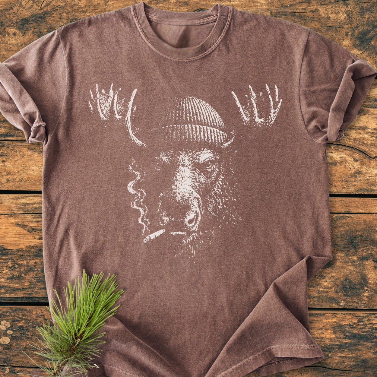 Slow Burn Moose - Vintage Wash Tee: brown short-sleeve shirt features a stylized moose in a knit cap, cigarette in mouth, on rustic wood, emphasizing relaxed fit and durable, soft-washed cotton fabric.