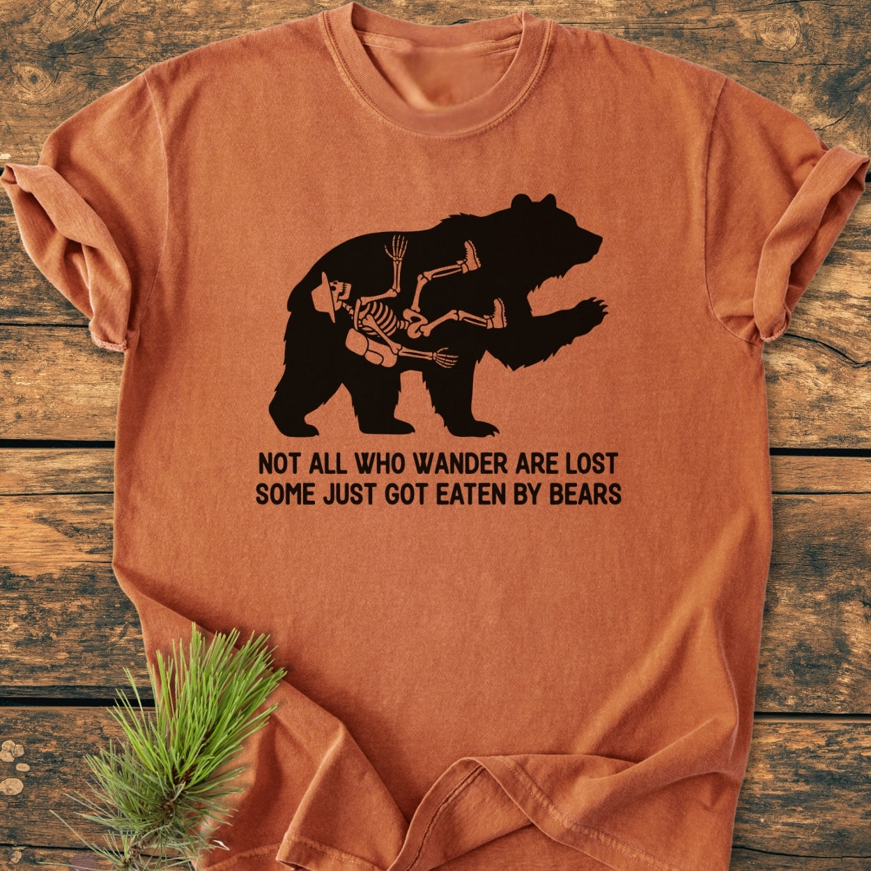 Not All Who Wander Are Lost - Vintage Wash Tee features a black bear silhouette with a hiker's skeleton inside and a playful slogan, highlighting its relaxed fit and durable construction.