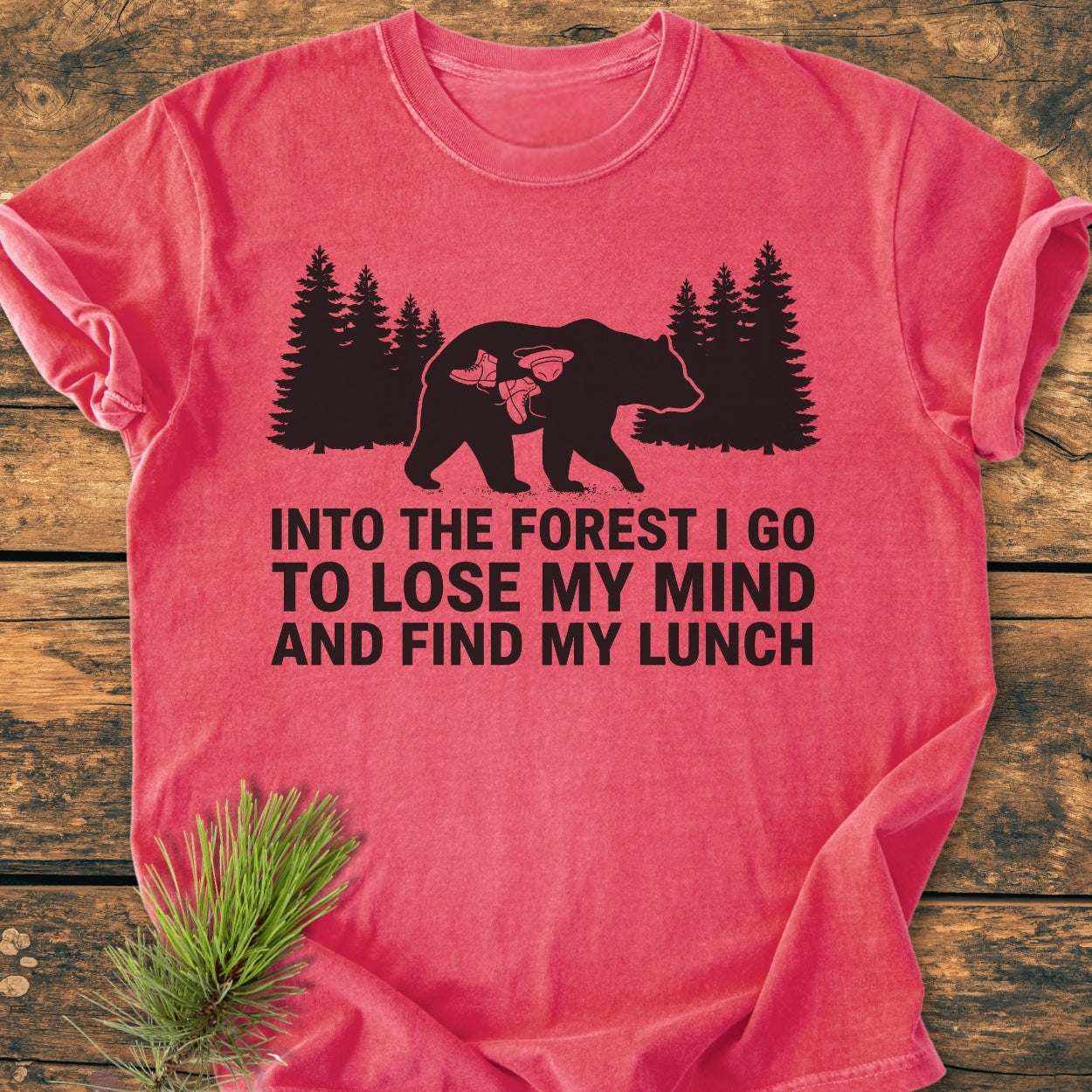 Into The Forest Bear - Vintage Wash Tee features a black bear graphic with hiking gear, pine trees, and a whimsical slogan on a heather-red fabric, embodying adventure and comfort.