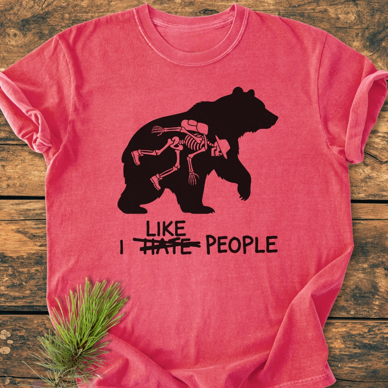 I Hate People - Vintage Wash Tee featuring a bear with hiker skeleton print, scribbled text, laid on wood. Soft, durable, garment-dyed, relaxed fit made from 100% ring-spun cotton.