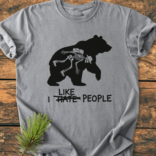 Heather-gray I Hate People - Vintage Wash Tee featuring a bear silhouette with a skeleton inside, styled with a sprig of pine needles on a rustic wood surface. Relaxed fit for everyday comfort.