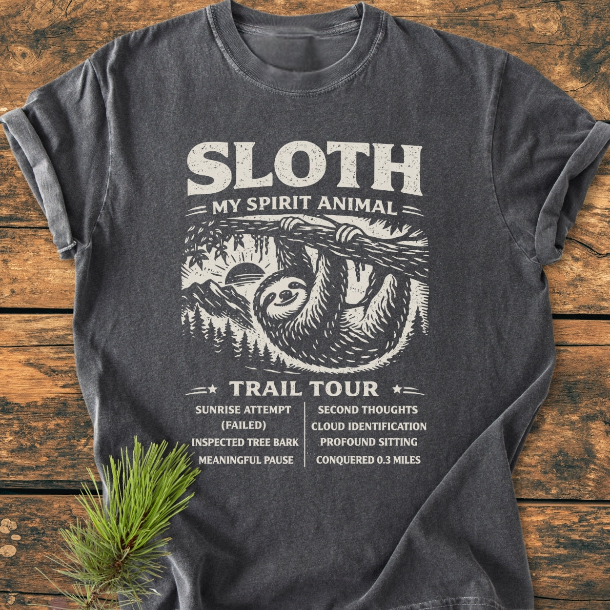 Sloth Spirit Animal Tour - Vintage Wash Tee features a distressed sloth graphic with humorous tour stops, printed on a flat-laid charcoal-gray T-shirt, embodying coziness and relaxed fit.