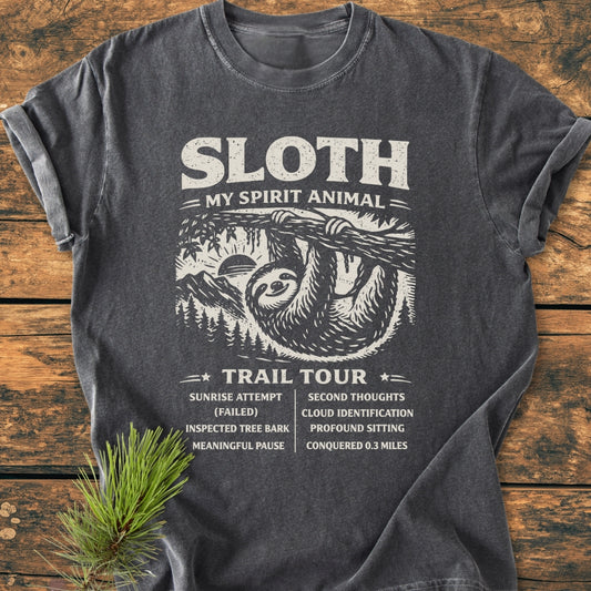 Sloth Spirit Animal Tour - Vintage Wash Tee features a distressed sloth graphic with humorous tour stops, printed on a flat-laid charcoal-gray T-shirt, embodying coziness and relaxed fit.