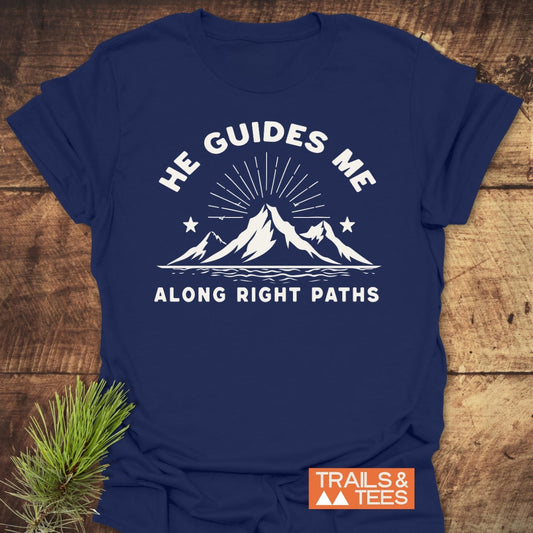 He Guides Me T-Shirt features a stylized mountain range with sunrays and stars, promoting outdoor adventure. Crafted from soft ring-spun cotton, it ensures comfort and durability, perfect for nature enthusiasts.