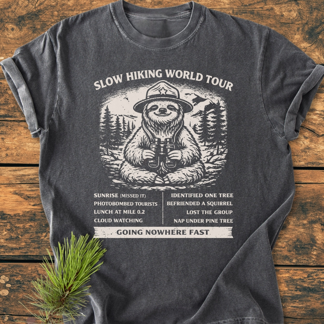 Slow Hiking World Tour - Vintage Wash Tee featuring a cartoon sloth in a ranger hat with binoculars, surrounded by a humorous hiking itinerary. Ideal for cozy, relaxed wear.