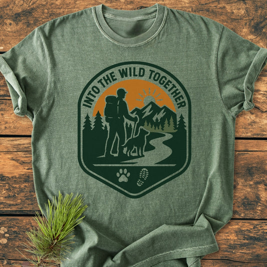 Into The Wild Together - Vintage Wash Tee features a badge with a hiker, dog, trail, and mountains, highlighting adventure. Crafted from 100% ring-spun cotton for comfort and durability.