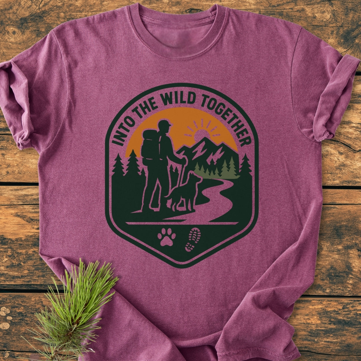 Into The Wild Together - Vintage Wash Tee features a heathered plum-purple color with an outdoor-adventure badge, showing a hiker and dog with mountains, paw, and boot prints.