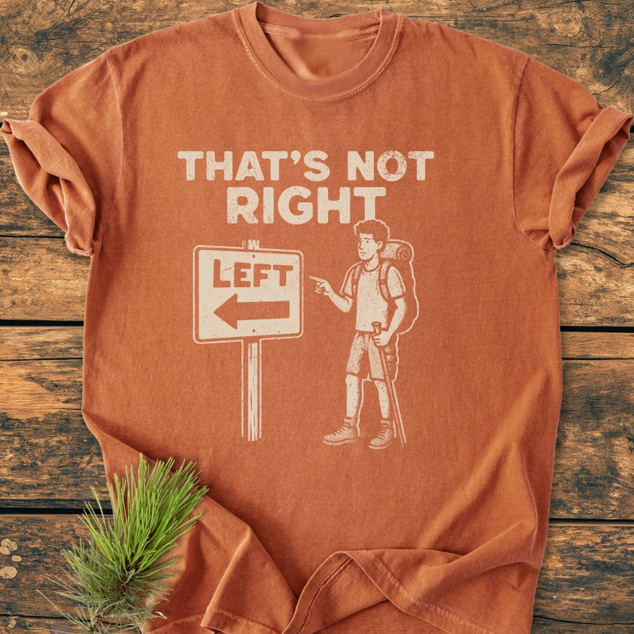 That's Not Right - Vintage Wash Tee features a distressed graphic of a hiker pointing left at a sign. Laid on wood, this Comfort Colors 1717 tee is soft-washed, cozy, and durable.