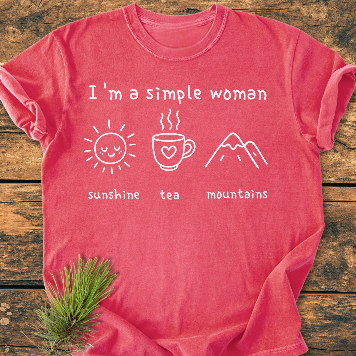 I'm A Simple Woman. Sunshine, Tea, Mountains - Vintage Wash Tee on wooden surface with pine sprig, features cozy garment-dyed 100% ring-spun cotton, relaxed fit, durable stitching, and simplistic line-drawings.