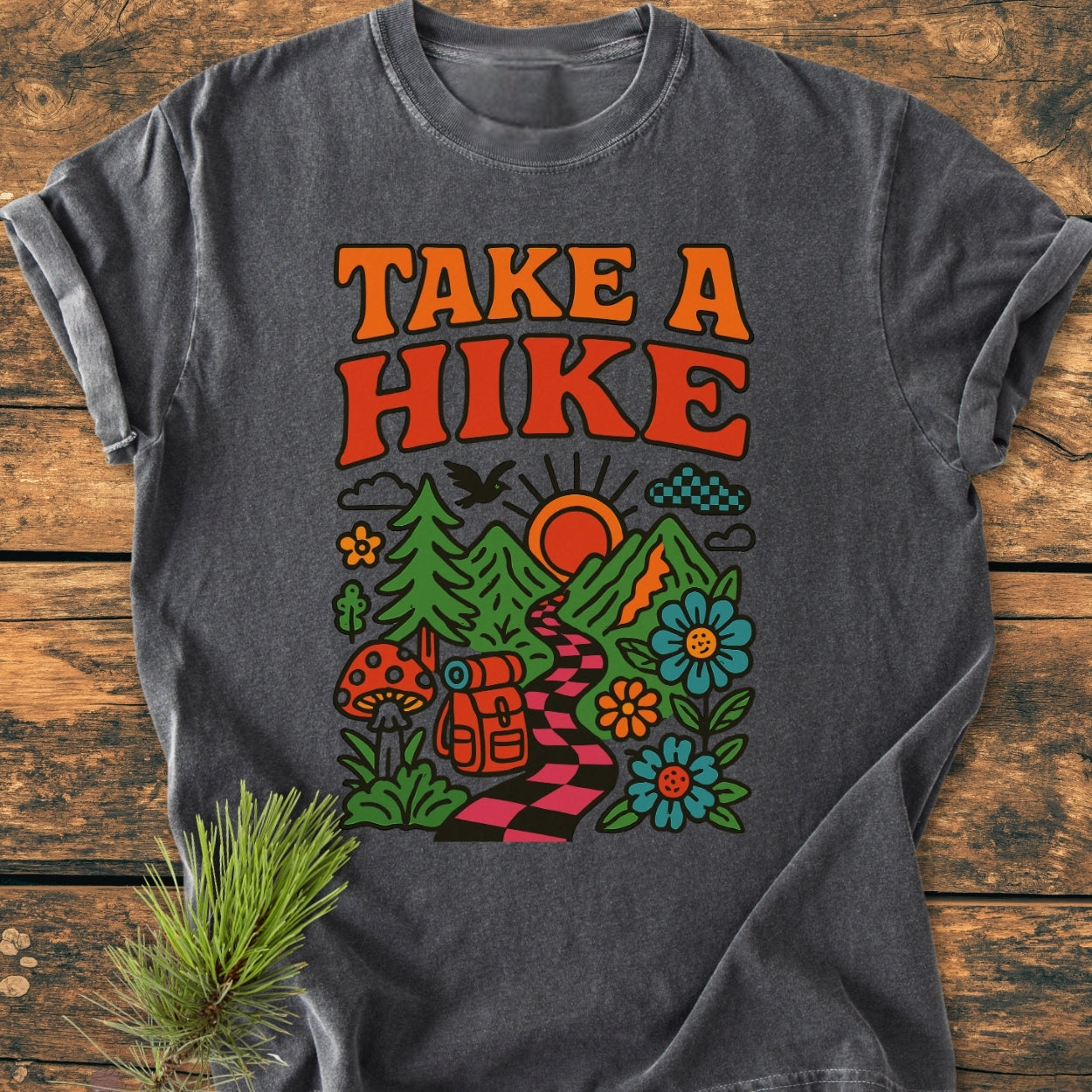 Take A Hike Funky - Vintage Wash Tee features a retro nature graphic with TAKE A HIKE lettering, a campsite scene, and pine needles, illustrating an outdoorsy, adventurous theme.