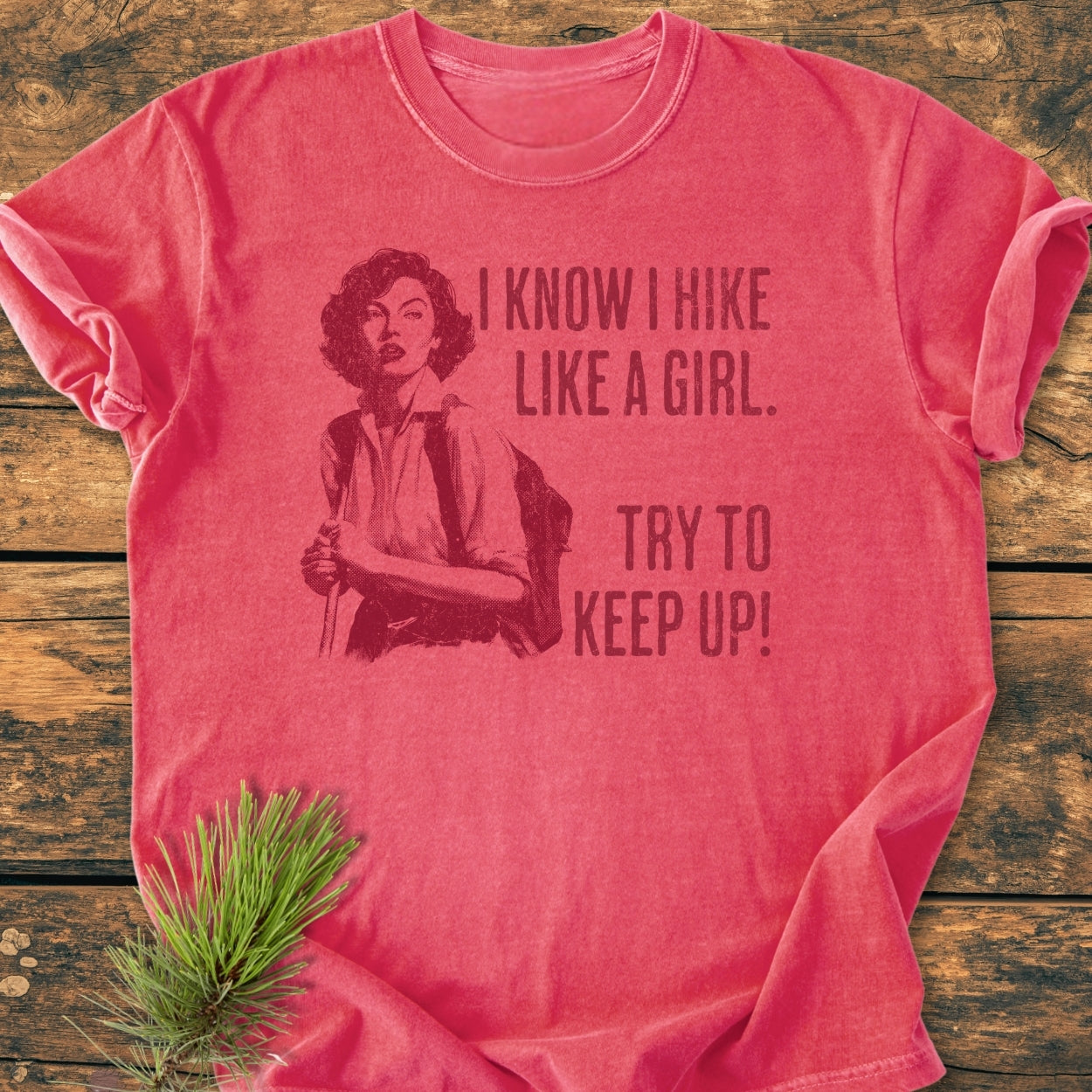 Hike Like A Girl - Vintage Wash Tee features a vintage-style illustration of a woman hiking. The red crew-neck T-shirt, laid flat, showcases the bold slogan, offering a cozy, relaxed fit.