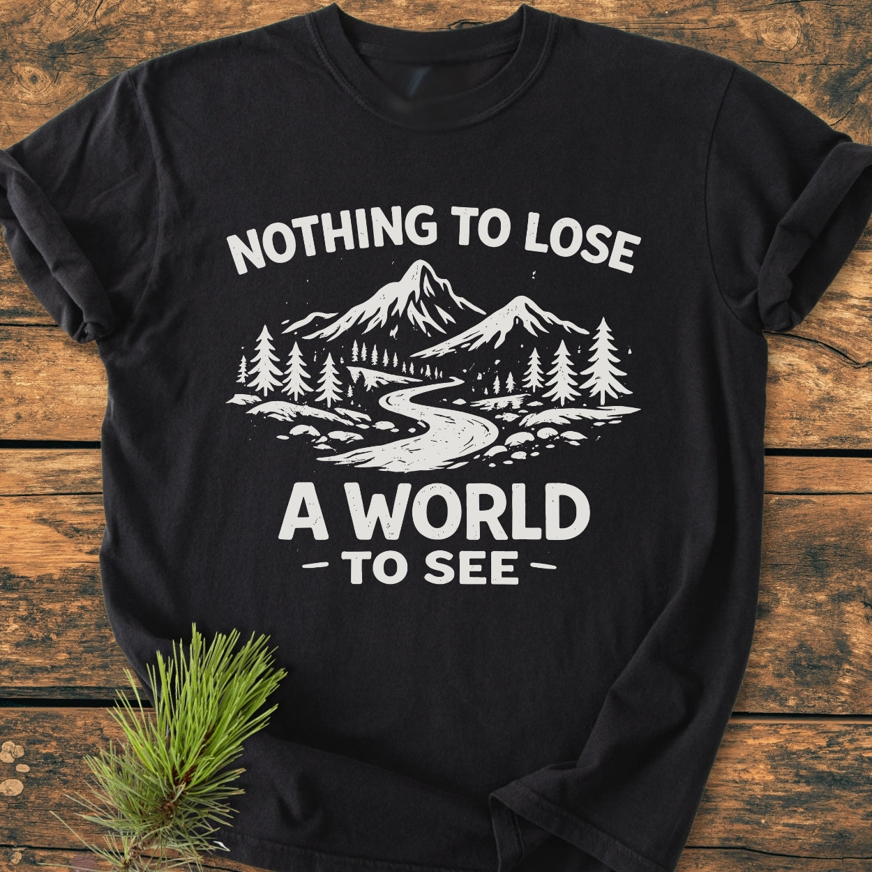 Nothing To Lose - Vintage Wash Tee features a stylized outdoor scene with mountains, river, and pine trees on a flat-laid black t-shirt, showcasing a relaxed fit and durable design.