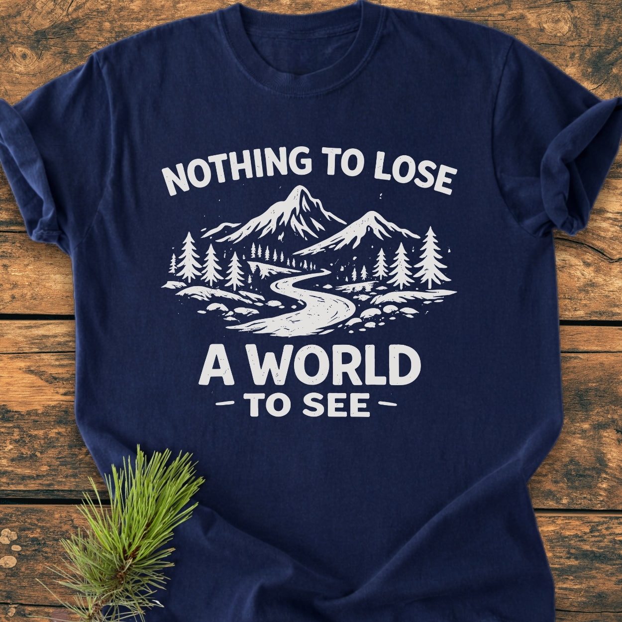 Nothing To Lose - Vintage Wash Tee features a stylized outdoor scene with mountains and river, printed on a navy-blue T-shirt, showcasing its cozy, relaxed fit and durable design on a wooden surface.