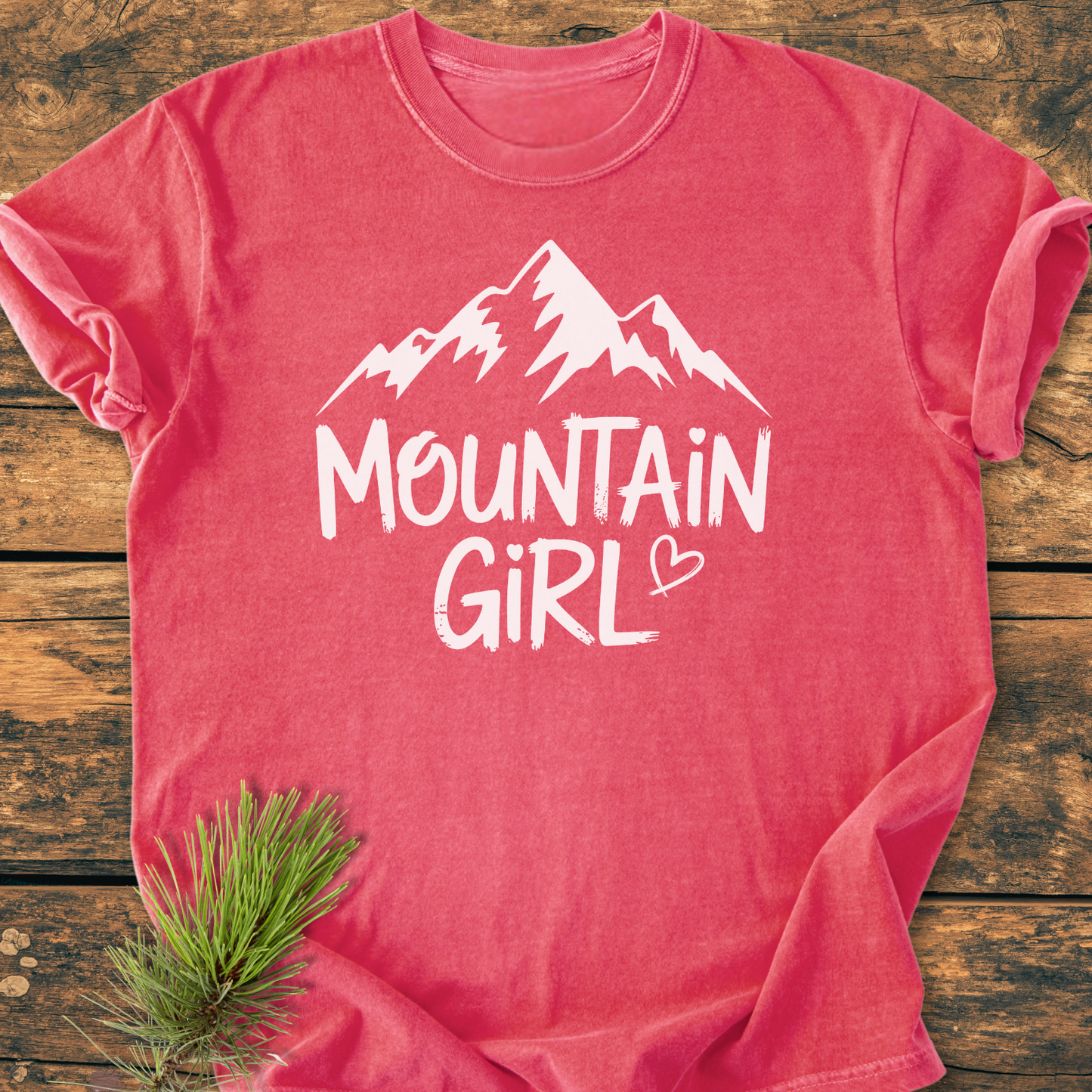 Mountain Girl - Vintage Wash Tee features a pink/red hue with a mountain silhouette and MOUNTAIN GIRL text. Soft cotton, relaxed fit, and durable stitching ensure comfort and longevity.