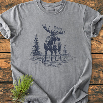 Moose - Vintage Wash Tee featuring a line-art bull moose design, laid on rustic wood. Soft-washed, 100% ring-spun cotton, relaxed fit, durable double-needle stitching, with a pine sprig accent.