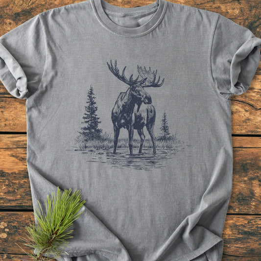 Moose - Vintage Wash Tee featuring a line-art bull moose design, laid on rustic wood. Soft-washed, 100% ring-spun cotton, relaxed fit, durable double-needle stitching, with a pine sprig accent.