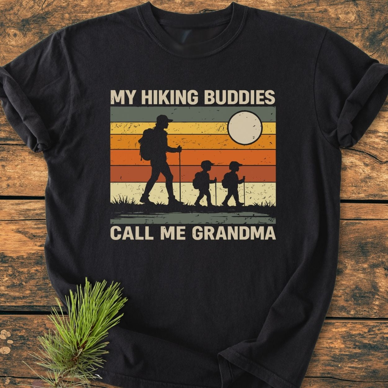 My Hiking Buddies Call Me Grandma - Vintage Wash Tee features a retro sunset-striped hiking graphic on a dark T-shirt, highlighting a cozy, relaxed fit with durable double-needle stitching and soft-washed fabric.