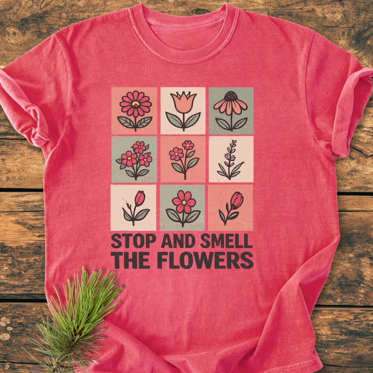 Stop And Smell The Flowers - Vintage Wash Tee displayed on wood, showcasing a 3x3 grid of hand-drawn flowers with the phrase beneath. Features soft-washed, garment-dyed fabric for a cozy, relaxed fit.