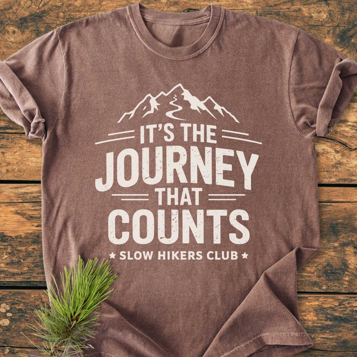 It's The Journey That Counts - Vintage Wash Tee features a mountain graphic and slogan, laid on wood with a pine sprig. Short-sleeve, brown, relaxed fit, 100% ring-spun cotton.