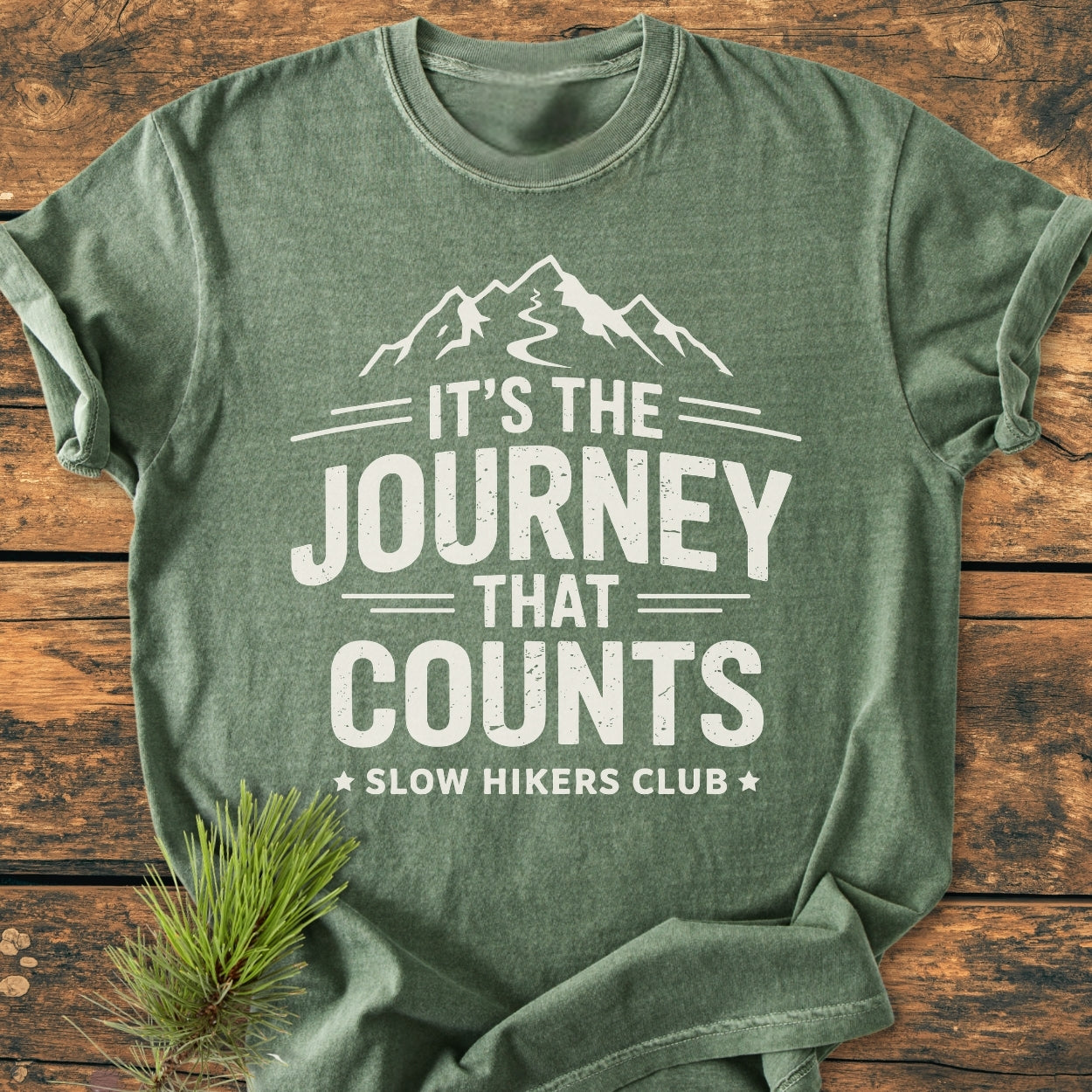 It's The Journey That Counts - Vintage Wash Tee featuring a mountain graphic and slogan, laid flat with a pine sprig. Made of cozy, pre-shrunk, ring-spun cotton with a relaxed fit.