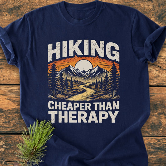 Hiking Cheaper Than Therapy - Vintage Wash Tee features a sunset mountain scene with pine trees and a trail. Made from 100% ring-spun cotton, it offers a relaxed fit for daily comfort.
