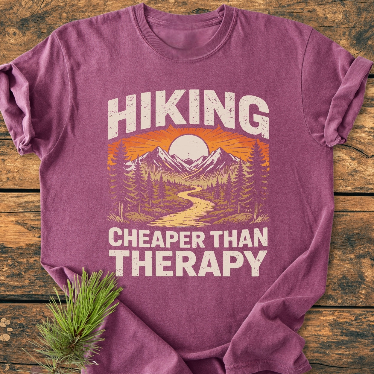 The Hiking Cheaper Than Therapy - Vintage Wash Tee features a stylized outdoors scene with mountains and a river, emphasizing comfort with a relaxed fit and durable, soft-washed 100% ring-spun cotton.