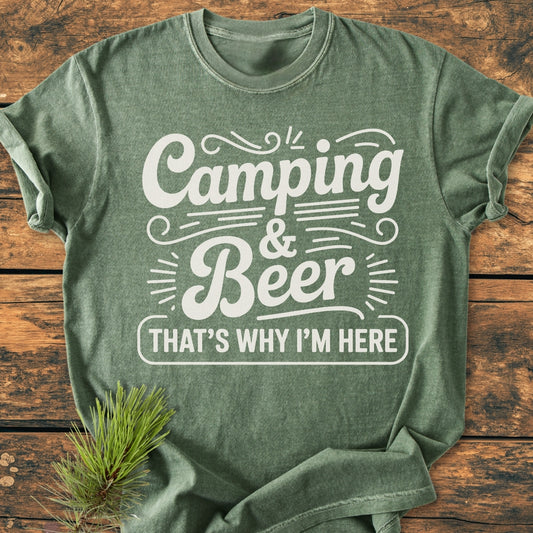 Forest-green Camping And Beer - Vintage Wash Tee with white hand-lettered text on a rustic wooden surface, accompanied by a pine sprig, highlighting its outdoor appeal and relaxed fit.