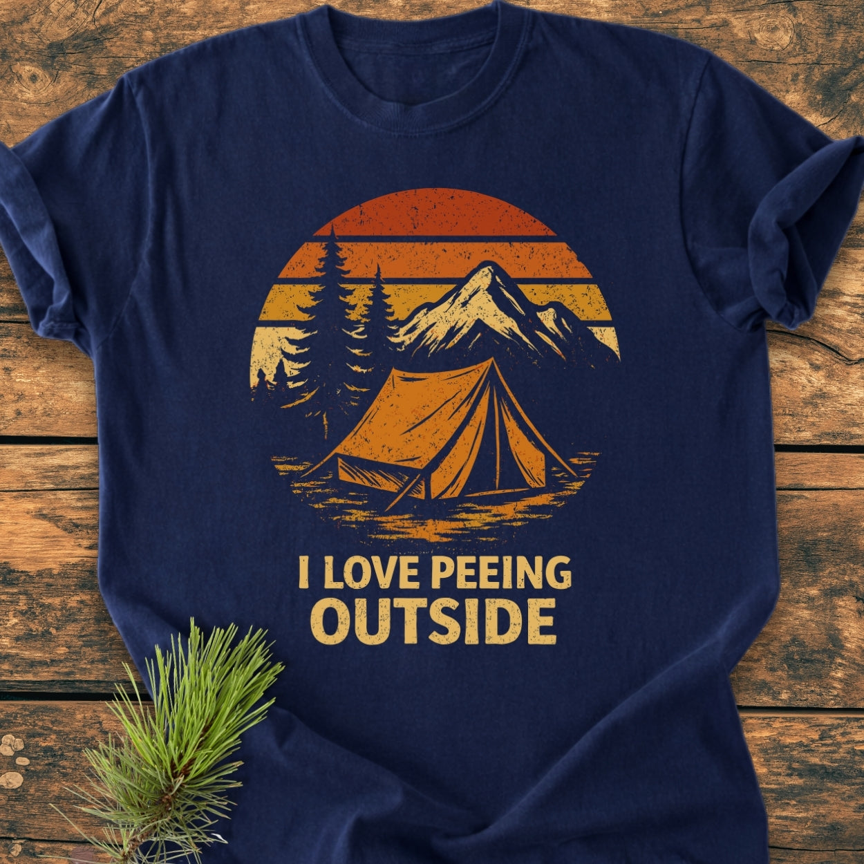 Navy-blue I LOVE Peeing Outside - Vintage Wash Tee with a sunset, mountains, trees, and tent graphic. Laid on wood, showcasing durable, soft-washed garment-dyed cotton with a relaxed fit.