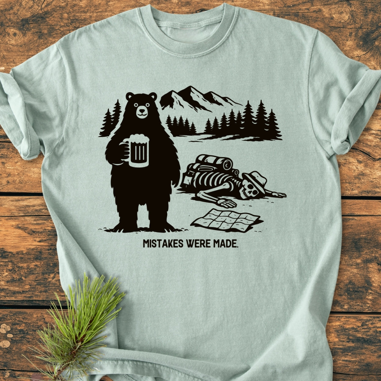 Mistakes Were Made - Vintage Wash Tee features a cartoon bear with a beer, a human skeleton with a map, and a wilderness backdrop, captioned humorously with MISTAKES WERE MADE.